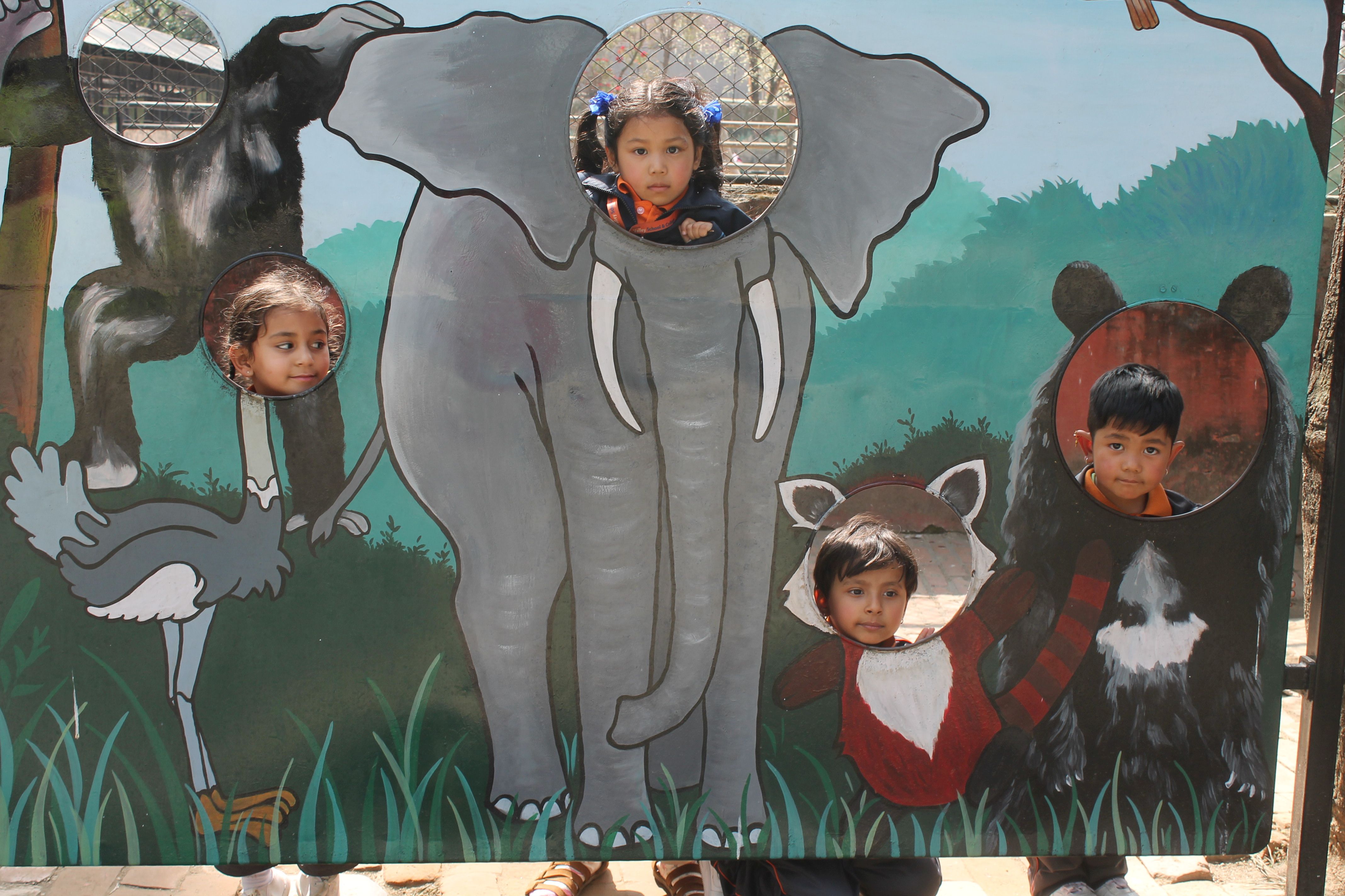 children are showing face from the animal body in zoo
